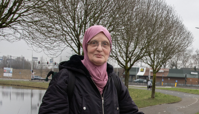 Een ingezoomde foto van Chahida el Mossoui, met roze hoofddoek, die buiten staat en naar de camera kijkt.